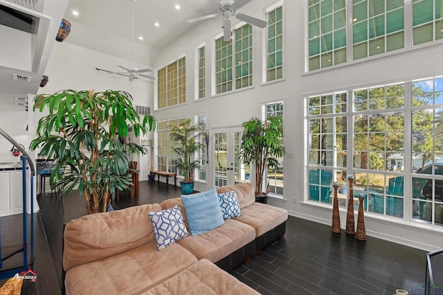 living room with a wealth of natural light, dark wood-type flooring, french doors, and ceiling fan