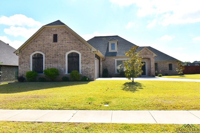 french country home featuring a garage and a front yard