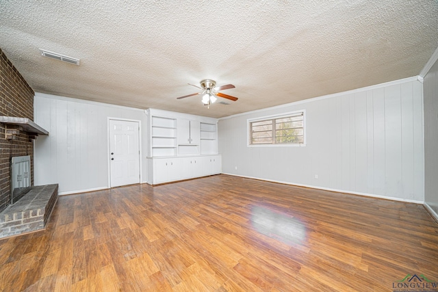 unfurnished living room featuring ceiling fan, hardwood / wood-style floors, a textured ceiling, and a fireplace