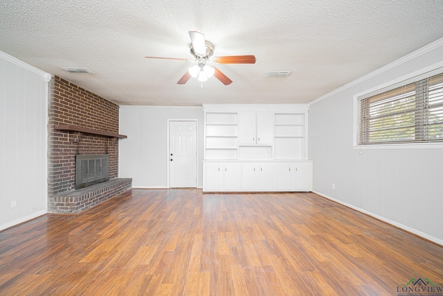 unfurnished living room featuring ornamental molding, a brick fireplace, dark wood-type flooring, and a textured ceiling