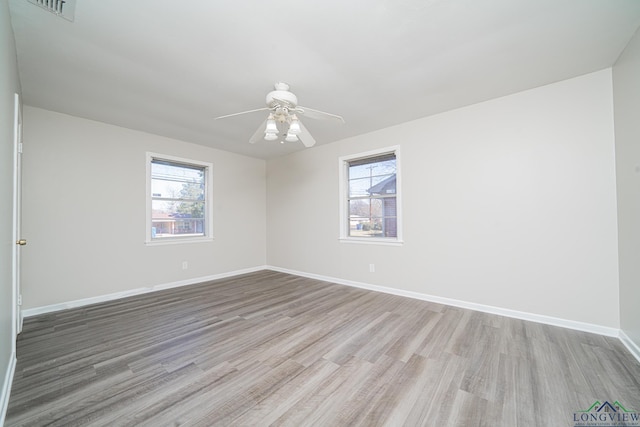 spare room with ceiling fan, a wealth of natural light, and light hardwood / wood-style floors