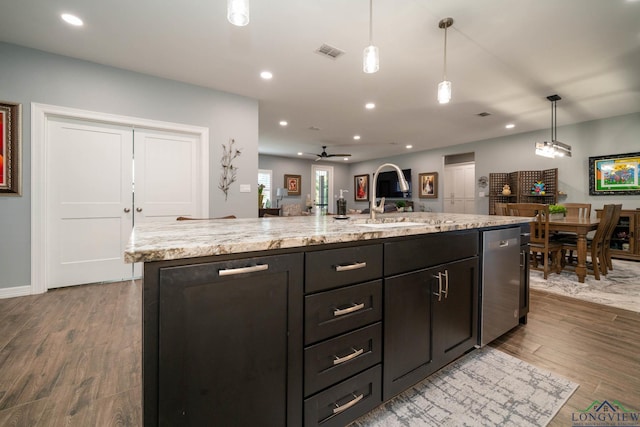 kitchen featuring ceiling fan, pendant lighting, a kitchen island with sink, and light wood-type flooring