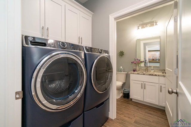 laundry area featuring cabinets, wood-type flooring, and separate washer and dryer