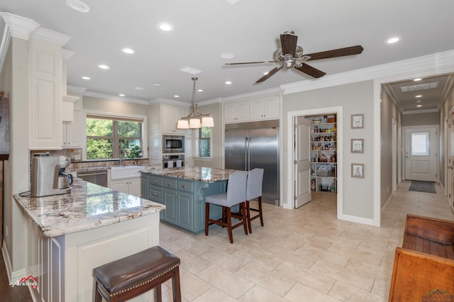 kitchen with a kitchen bar, built in appliances, light stone countertops, and a kitchen island