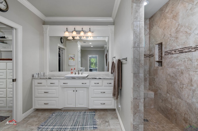 bathroom featuring a tile shower, crown molding, and vanity