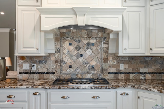 kitchen with tasteful backsplash, white cabinetry, premium range hood, and stainless steel gas stovetop