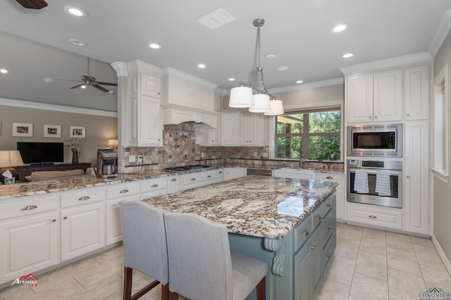 kitchen with light stone countertops, a kitchen breakfast bar, stainless steel appliances, a kitchen island, and white cabinetry