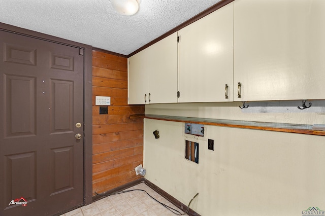 clothes washing area featuring cabinets, washer hookup, wood walls, a textured ceiling, and ornamental molding