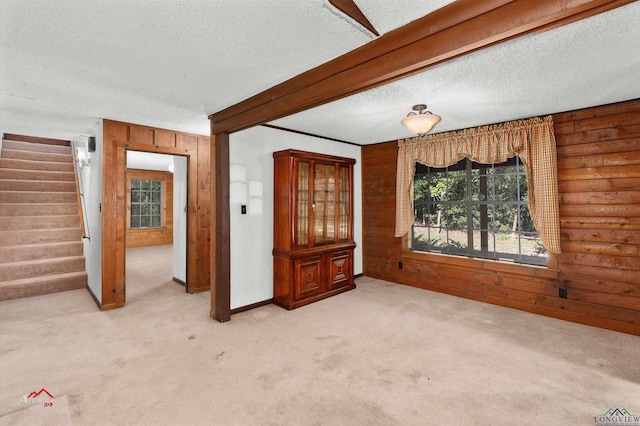 interior space featuring a textured ceiling, wooden walls, and log walls