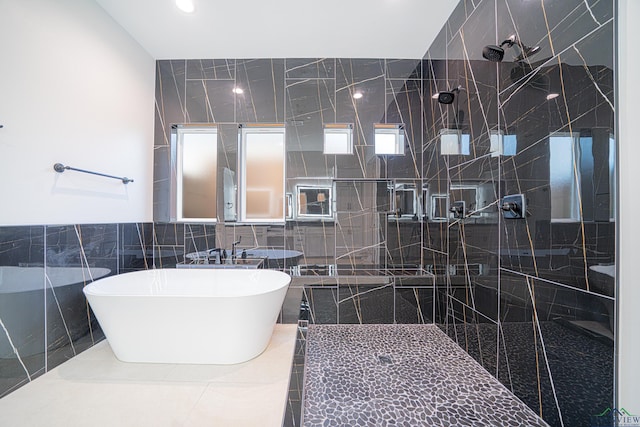 bathroom with sink, independent shower and bath, and tile walls