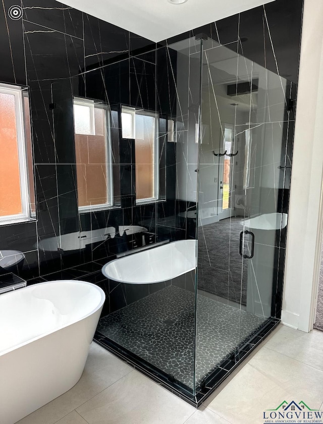 bathroom featuring tile patterned flooring, a shower with door, and tile walls