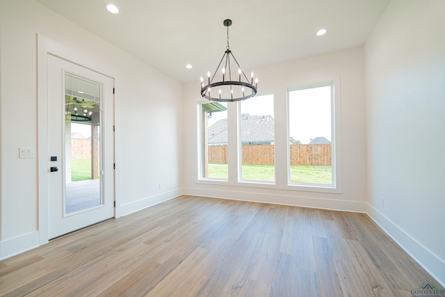 unfurnished dining area featuring light hardwood / wood-style floors and a notable chandelier