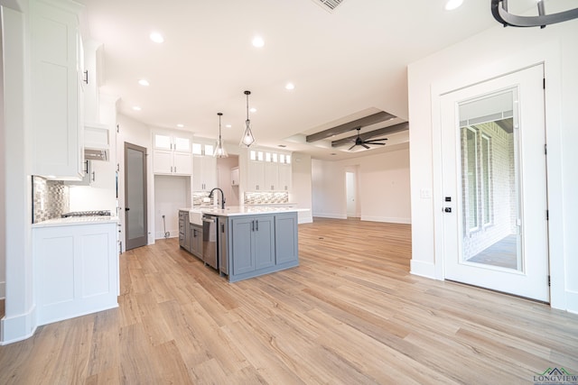 kitchen with a kitchen island with sink, white cabinetry, and pendant lighting