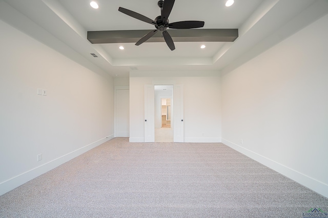 unfurnished room with ceiling fan, a raised ceiling, and light carpet