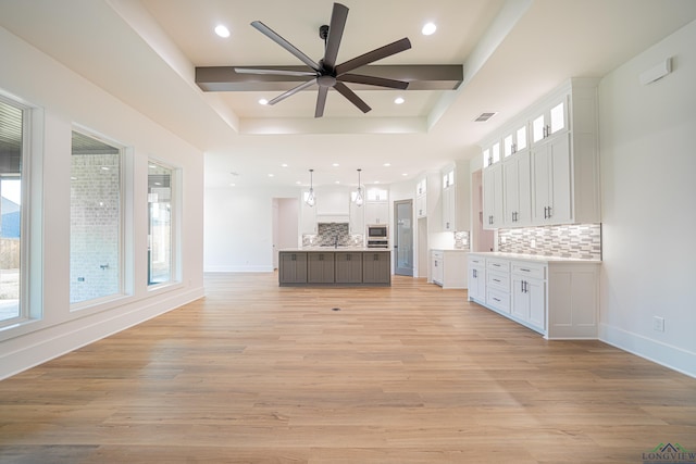 kitchen with tasteful backsplash, white cabinetry, a kitchen island, and decorative light fixtures