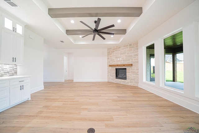 unfurnished living room featuring a fireplace, beam ceiling, light hardwood / wood-style flooring, and ceiling fan