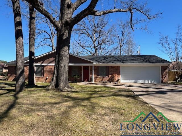 ranch-style house with driveway, brick siding, an attached garage, and a front yard