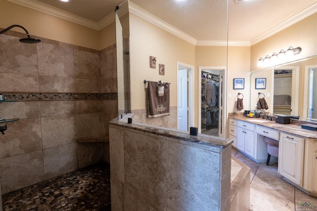 bathroom featuring tile patterned floors, vanity, a tile shower, and ornamental molding