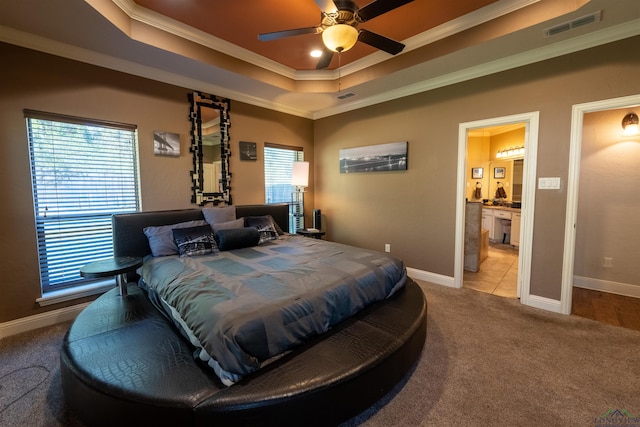 carpeted bedroom featuring connected bathroom, a raised ceiling, ceiling fan, and crown molding