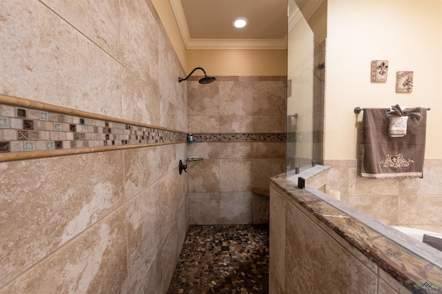 bathroom with a tile shower, crown molding, and tile walls