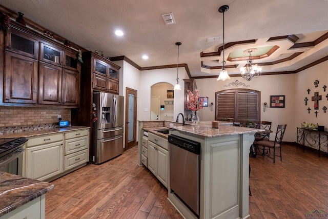 kitchen with crown molding, an island with sink, decorative light fixtures, dark brown cabinetry, and stainless steel appliances