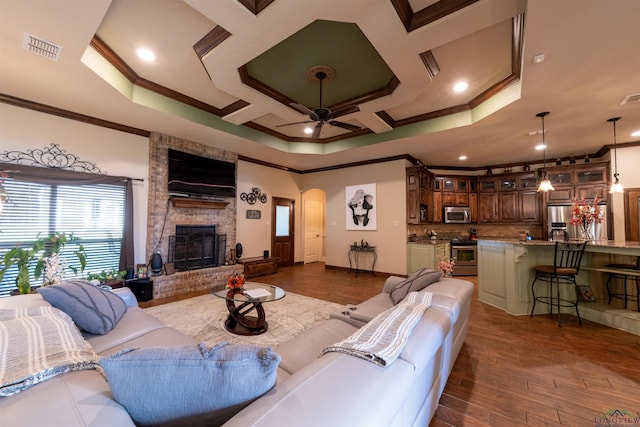 living room with dark hardwood / wood-style flooring, a brick fireplace, ceiling fan, and crown molding