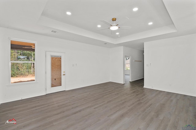 unfurnished living room featuring dark hardwood / wood-style floors, ceiling fan, and a raised ceiling