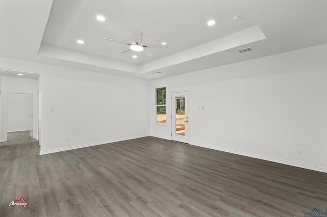 spare room with a raised ceiling, ceiling fan, and dark wood-type flooring