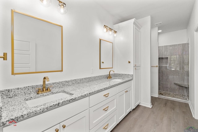 bathroom with hardwood / wood-style floors, vanity, and tiled shower