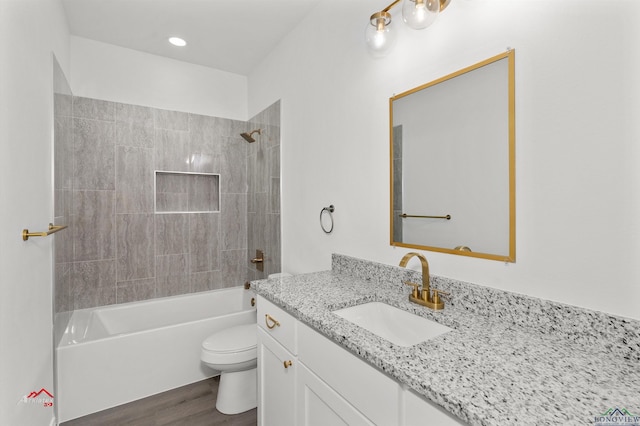 full bathroom with vanity, wood-type flooring, tiled shower / bath combo, and toilet