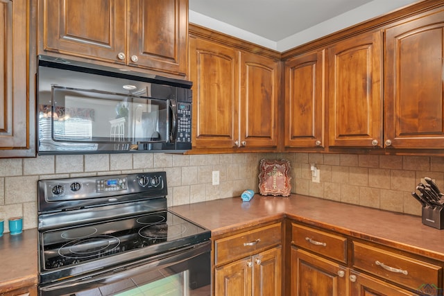 kitchen featuring brown cabinetry, black appliances, and tasteful backsplash