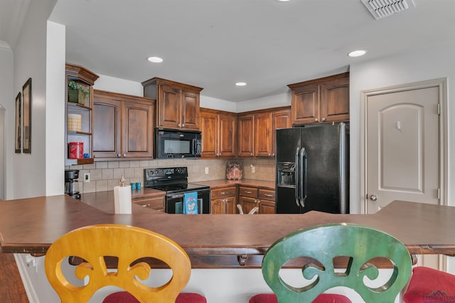 kitchen featuring decorative backsplash, a peninsula, visible vents, and black appliances