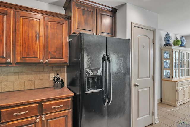 kitchen with decorative backsplash, black fridge with ice dispenser, baseboards, and light tile patterned floors