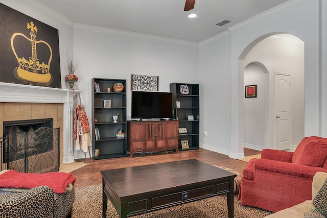 living room featuring ceiling fan, wood finished floors, arched walkways, and ornamental molding