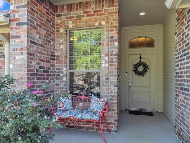 doorway to property with brick siding and a porch
