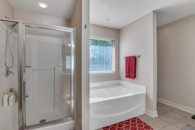 bathroom featuring a shower stall, a garden tub, tile patterned floors, and baseboards