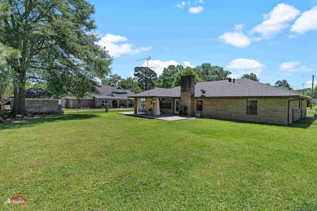 back of property featuring a chimney, a patio, brick siding, and a shingled roof