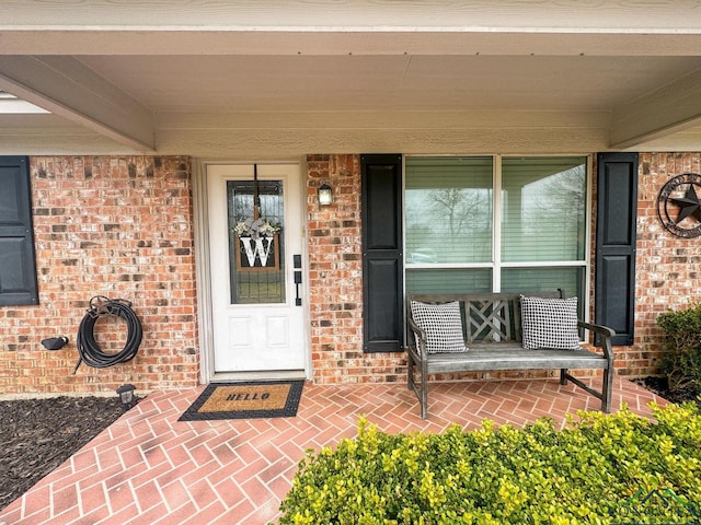 property entrance featuring brick siding and covered porch