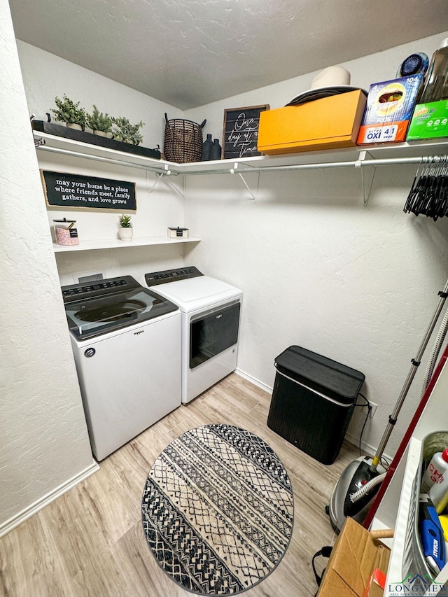 washroom with light wood finished floors, laundry area, washer and dryer, and baseboards