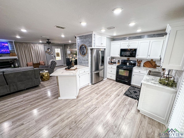 kitchen with visible vents, open floor plan, a peninsula, light wood-style floors, and black appliances