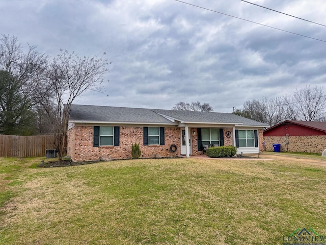 ranch-style house with brick siding, fence, roof with shingles, a front yard, and driveway