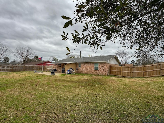 rear view of house featuring a patio area, a lawn, brick siding, and a fenced backyard