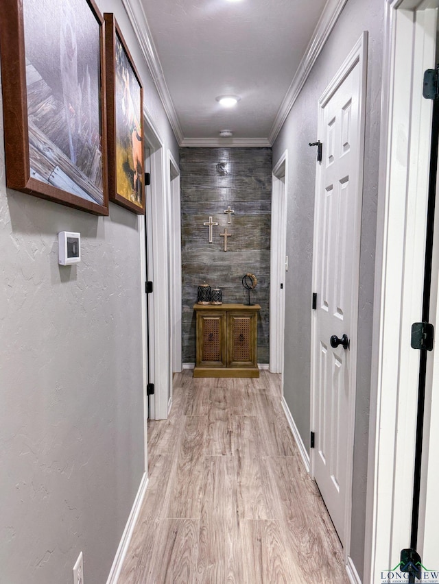 hallway featuring baseboards, crown molding, a textured wall, and wood finished floors