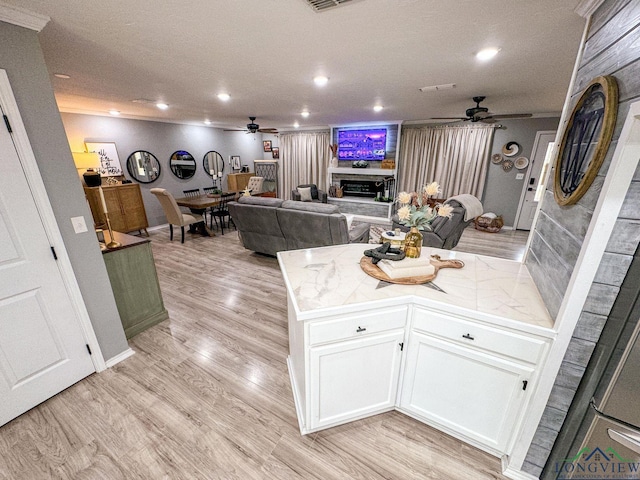 kitchen with light wood-type flooring, open floor plan, white cabinetry, recessed lighting, and a fireplace