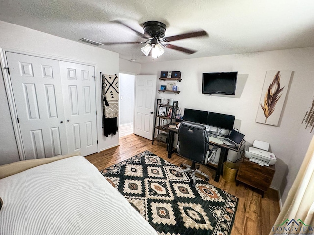 bedroom with a closet, visible vents, a textured ceiling, and wood finished floors