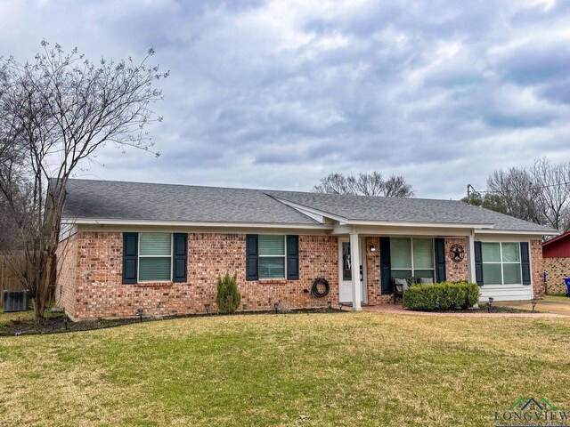 ranch-style home featuring brick siding, cooling unit, a shingled roof, and a front yard