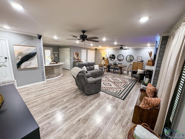 living room featuring ceiling fan, baseboards, ornamental molding, recessed lighting, and light wood-style floors