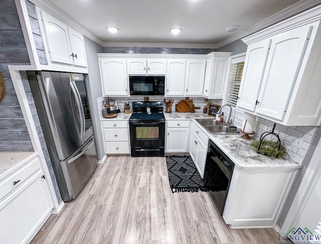 kitchen featuring black appliances, a sink, white cabinets, light wood finished floors, and decorative backsplash