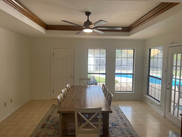 unfurnished dining area with a raised ceiling, a wealth of natural light, crown molding, and ceiling fan