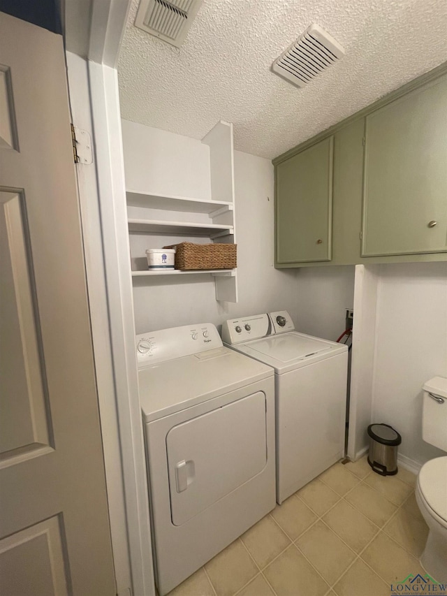 clothes washing area with separate washer and dryer, a textured ceiling, and light tile patterned floors